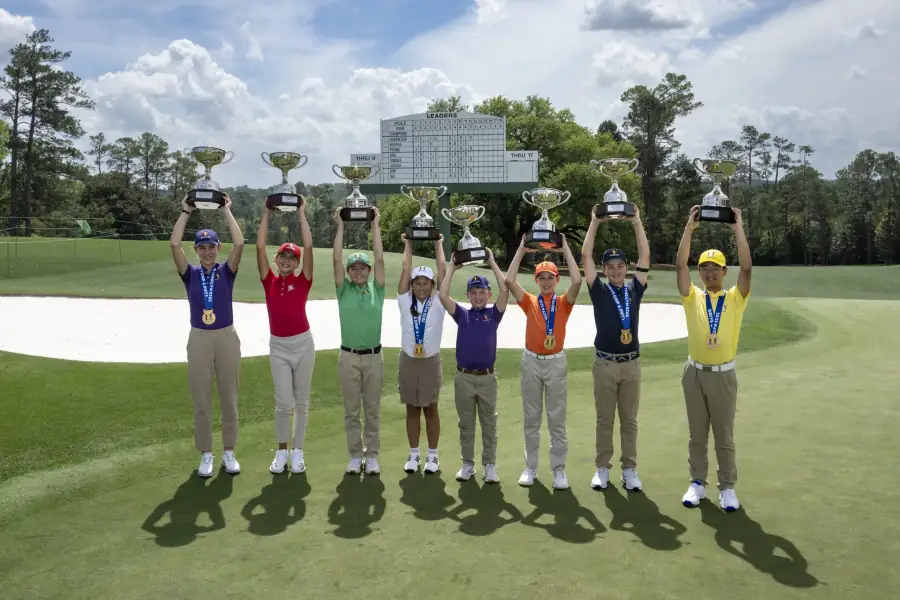 junior golfers holding trophies on the course